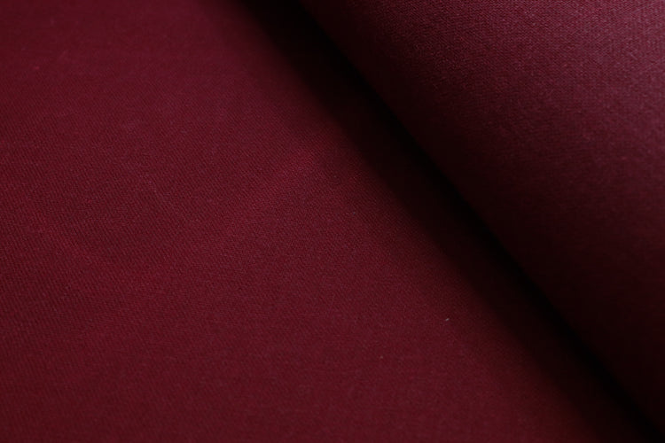 Close-up of waxed pink cotton canvas highlighting the subtle texture and light creases from the waxed finish.