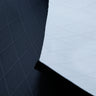 Close up of X-PAC VX21 nylon pack fabric in black showing the front and back of the fabric and the x-ply ripstop pattern