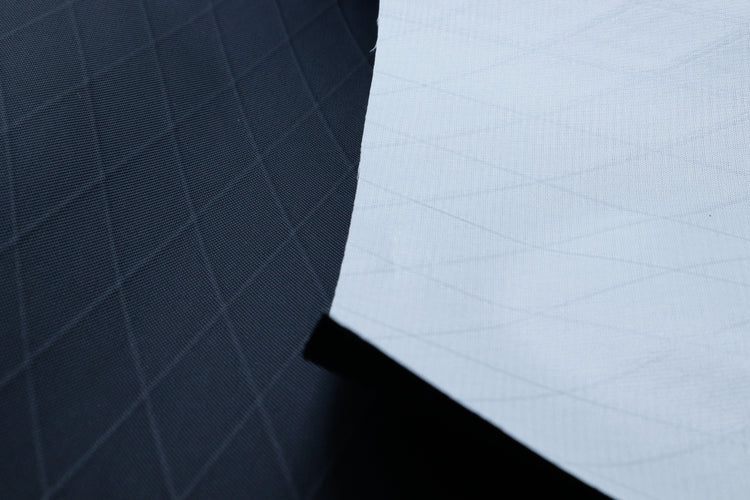 Close up of X-PAC VX21 nylon pack fabric in black showing the front and back of the fabric and the x-ply ripstop pattern