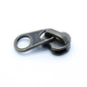 One antique brass YKK metal zipper slider with large circular pull tabs, displayed on a white background, showing size difference and vintage finish.