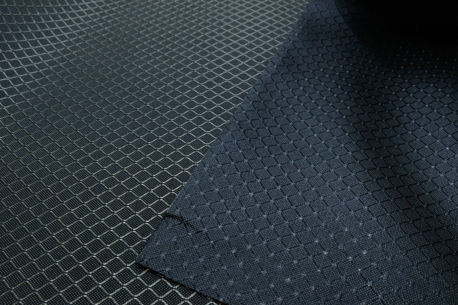 close-up of front and back of light grey diamond ripstop nylon fabric