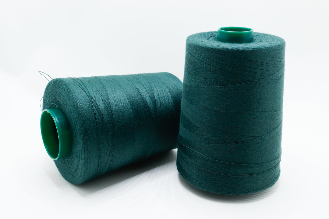 Two spools of teal thread on a white background