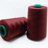 Two spools of red thread with green ends on a white background