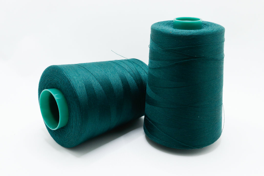 Two spools of teal thread on a white background