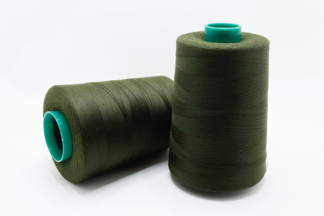 Two spools of green thread with teal ends on a white background