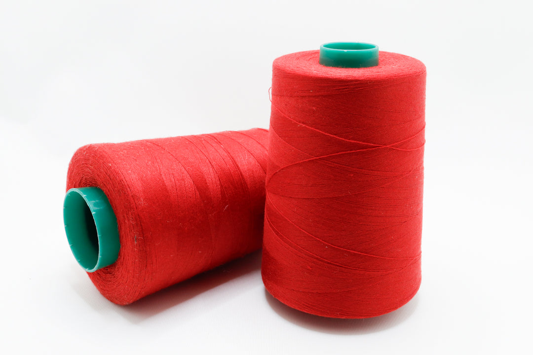 Two red spools of thread with green ends on a white background
