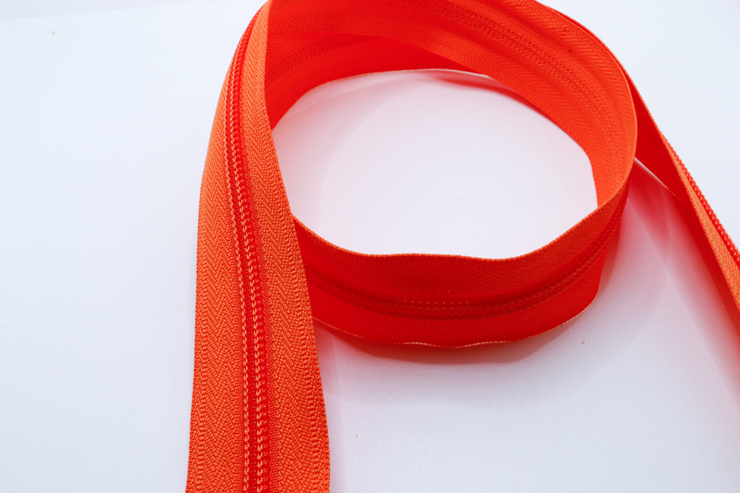 Orange YKK #5 coil zipper chain on a white background