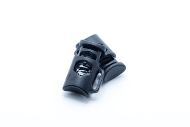 Black plastic cord lock with sewing loop shown from the side, anchored cord toggle for outdoor gear